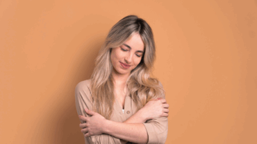 Woman smiling while holding herself, giving herself a hug