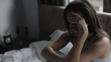 Woman is sad and depressed sitting in her bed