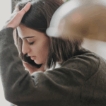 Young woman holding her head in her hand, looking stressed