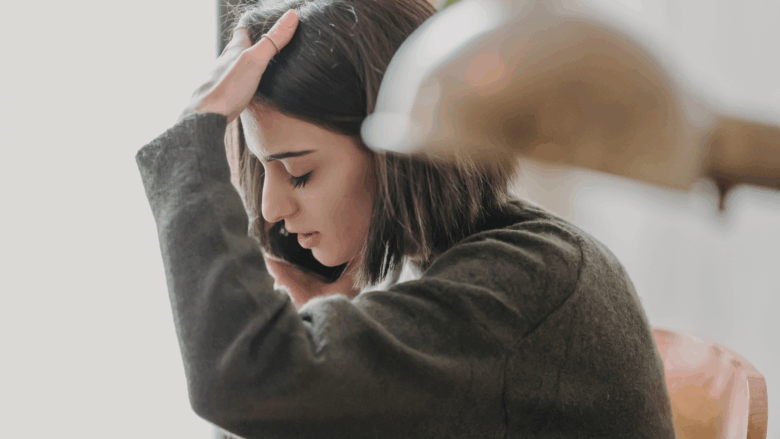Young woman holding her head in her hand, looking stressed