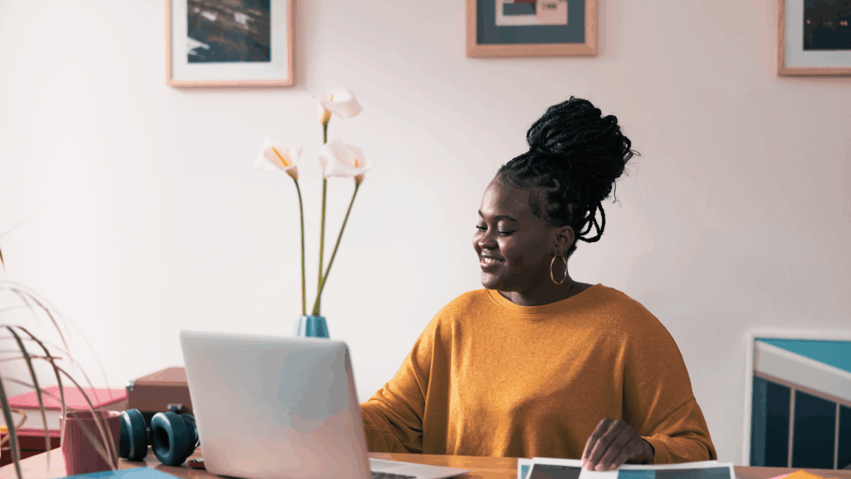 Lady wearing a mustard yellow coloured sweater working on her laptop at home